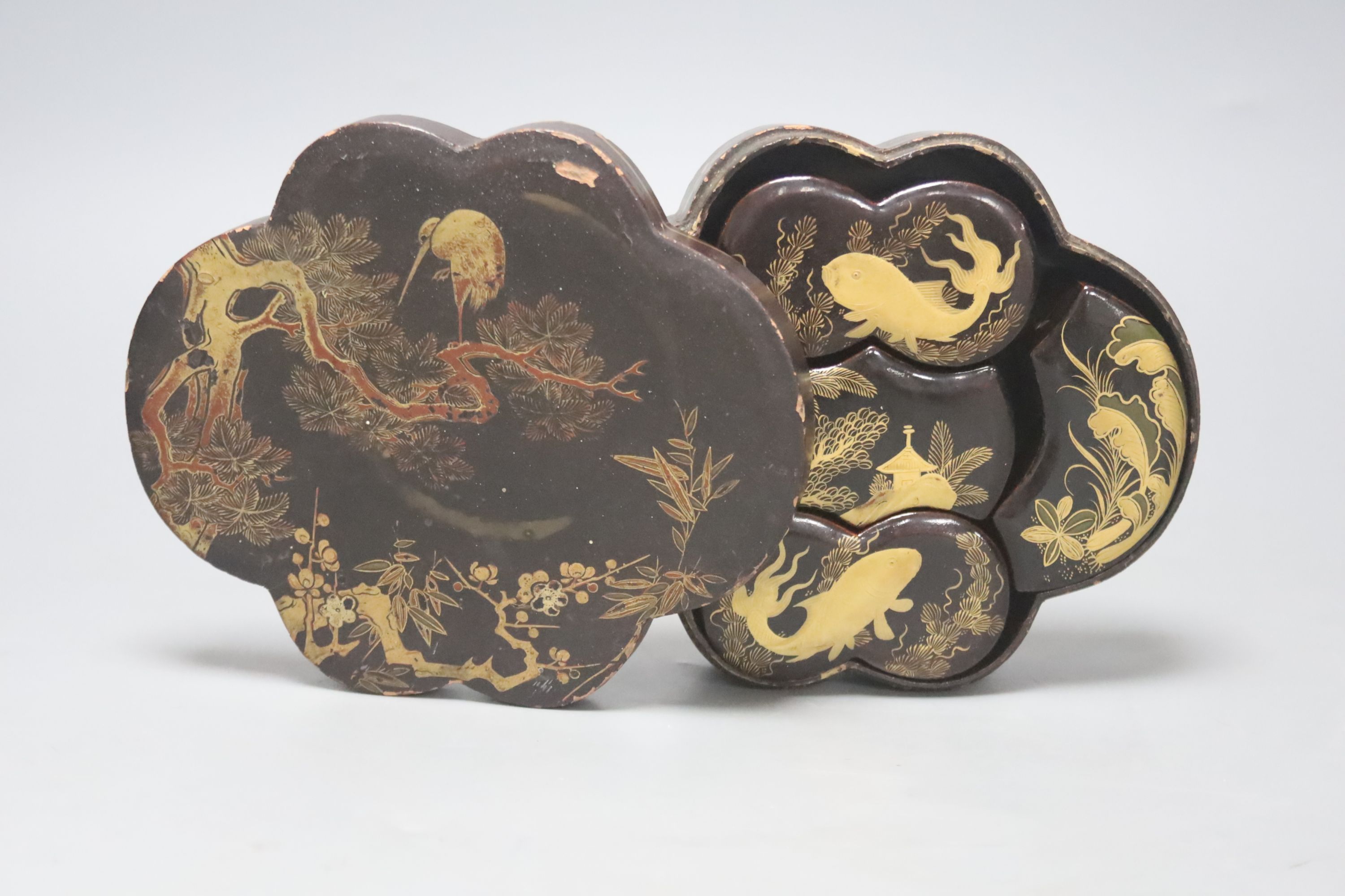 A Japanese black-lacquered box and cover, of shaped oval form, the top decorated in red and gilt with a stork on a branch, prunus, etc, L 16.5cm